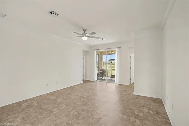 Spacious room featuring tile flooring, crown molding, and a ceiling fan