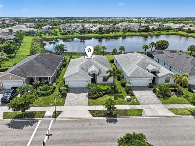 Single-story residence featuring a paved driveway, attached garage, manicured front landscaping, and a waterfront setting