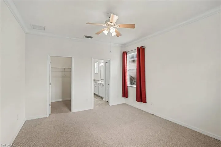 Carpeted flooring, ceiling fan, crown molding, double door openings, and a window with blinds