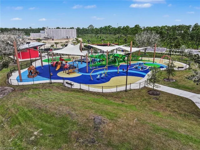 Playground featuring multiple play structures, a soft-fall surface, shade canopies, and a perimeter fence