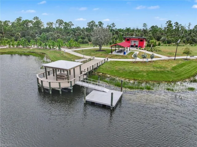 Waterfront property with a covered gazebo, extended dock, and a red-clad recreational building with an attached covered patio