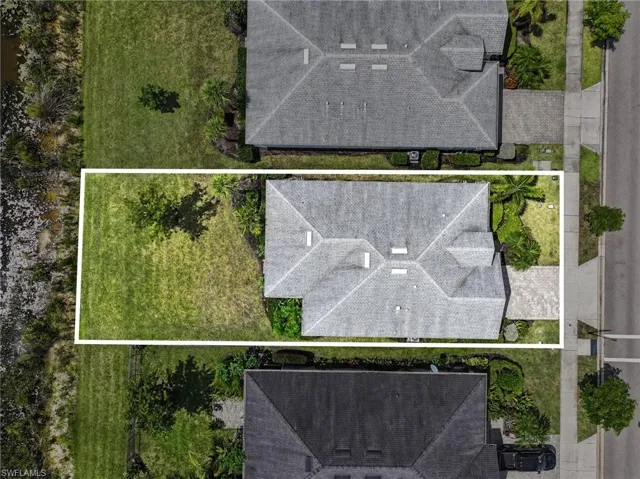 Aerial perspective showcasing a gabled roofline, mature trees, and a paved driveway