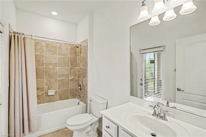 Bathroom featuring a shower/tub combination with tile surround, white vanity with integrated sink, and wall-mounted mirror