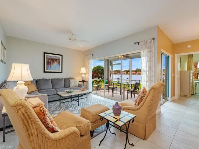 Living room with a ceiling fan, a water view, and light tile patterned flooring