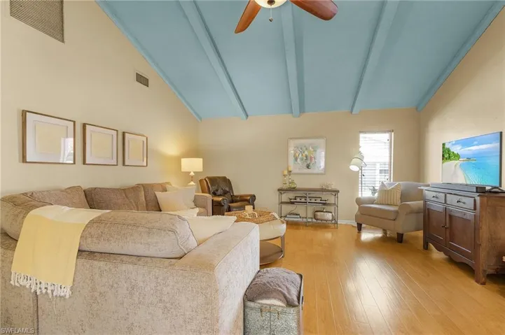 Living room with ceiling fan, high vaulted ceiling, beamed ceiling, and light wood-type flooring