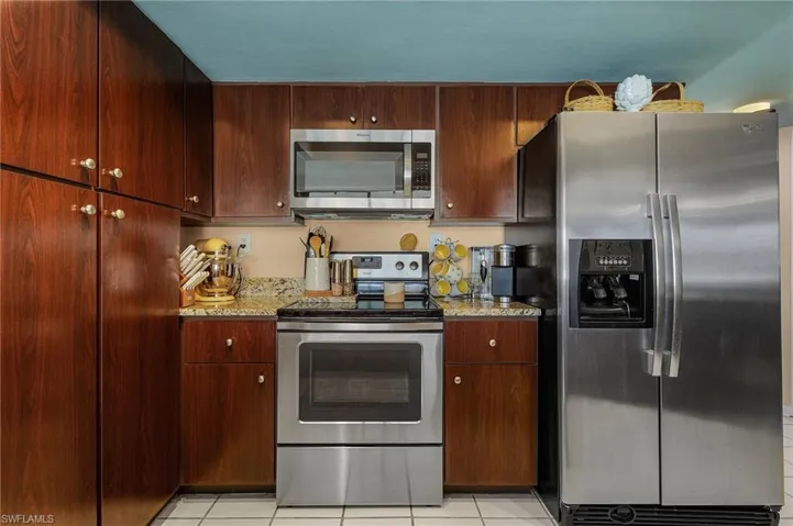 Kitchen featuring light stone countertops, appliances with stainless steel finishes, and light tile patterned flooring