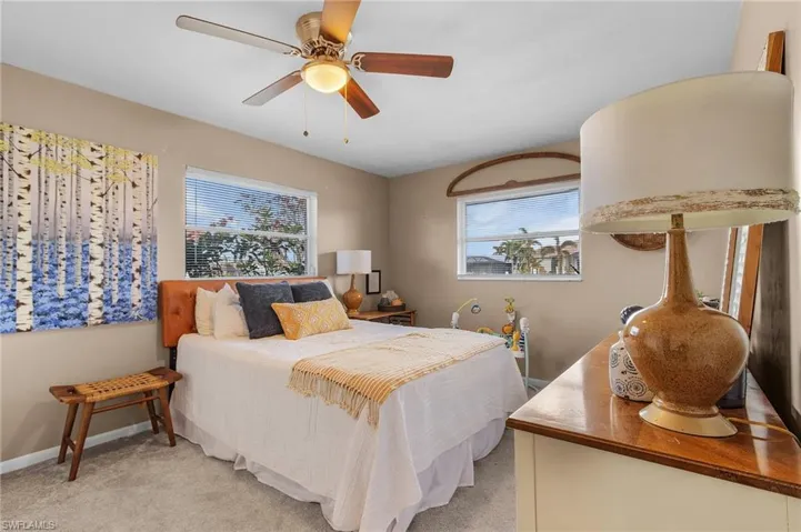 Bedroom featuring light carpet, multiple windows, and ceiling fan