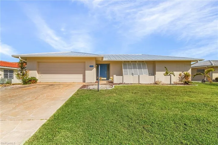 Single story home featuring a garage and a front lawn