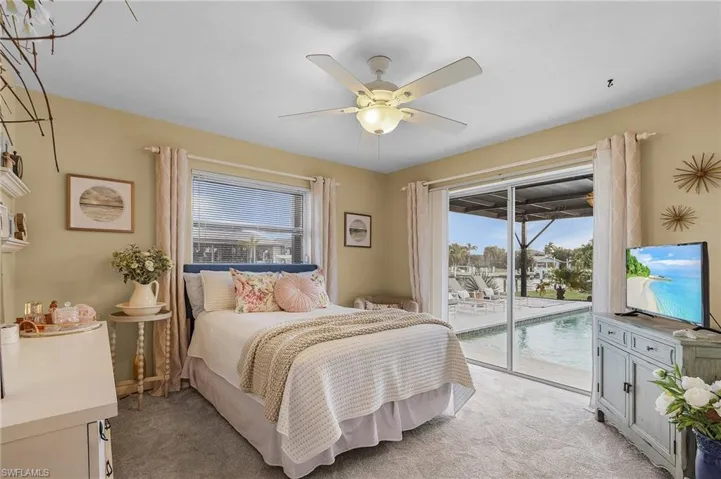 Carpeted bedroom with access to outside, multiple windows, and ceiling fan