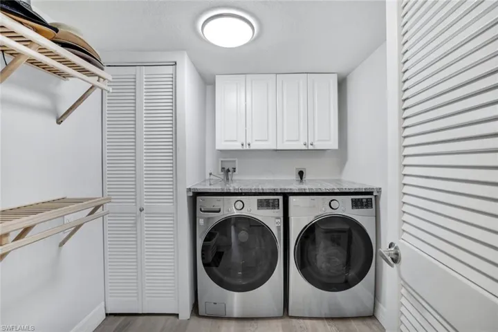 Laundry room with cabinets, light hardwood / wood-style flooring, and washing machine and clothes dryer