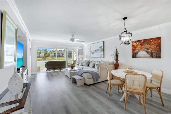 Living room with crown molding, Coretex vinyl floors, ceiling fan, and water feature view.