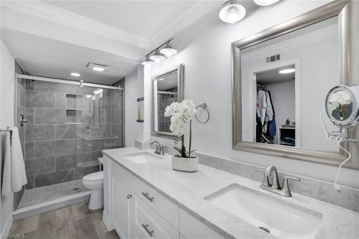 Primary bathroom with vanity, toilet, crown molding, walk in shower, Coretex vinyl flooring