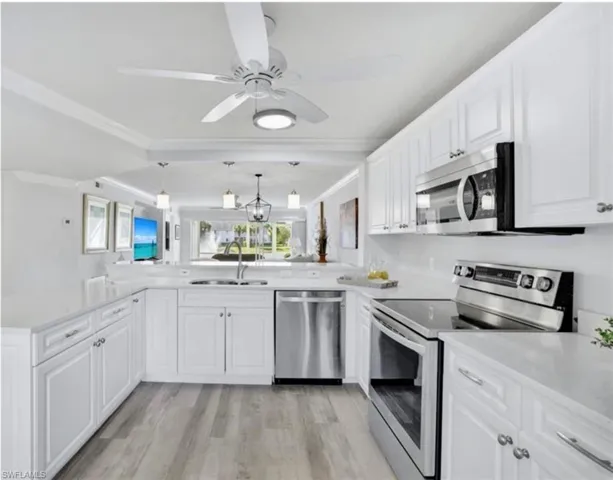 Kitchen with kitchen peninsula, sink, white cabinets, and stainless steel appliances