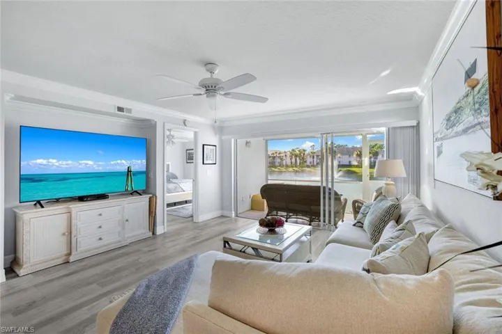 Living room with crown molding, Coretex vinyl floors, ceiling fan, and water feature view.