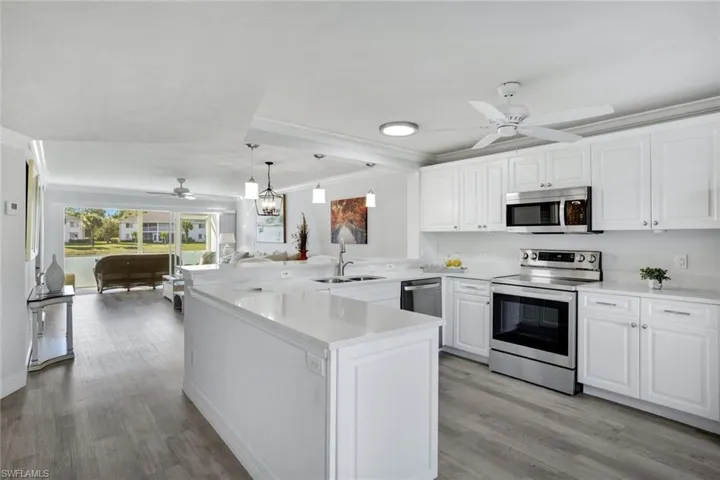 Kitchen featuring sink, kitchen peninsula, Coretex vinyl floors, white cabinetry, and stainless steel appliances