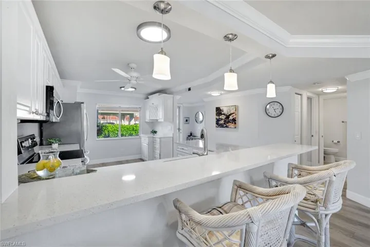 Spacious kitchen featuring appliances with stainless steel finishes, Coretex vinyl flooring, decorative glass pantry door, and white cabinetry