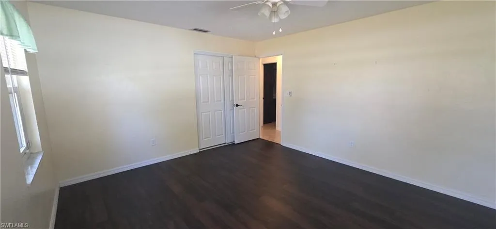 Unfurnished bedroom featuring dark wood-style floors, a ceiling fan, and a closet
