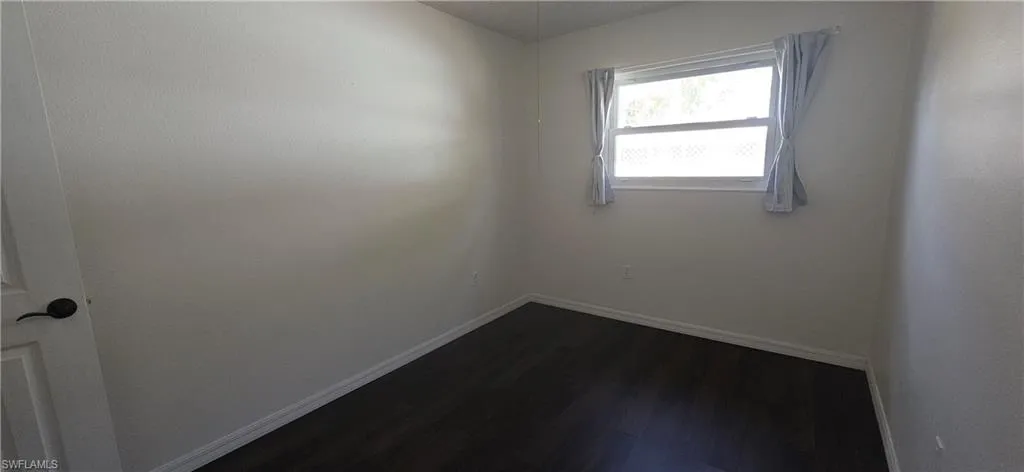 bedroom with baseboards and dark wood-style floors
