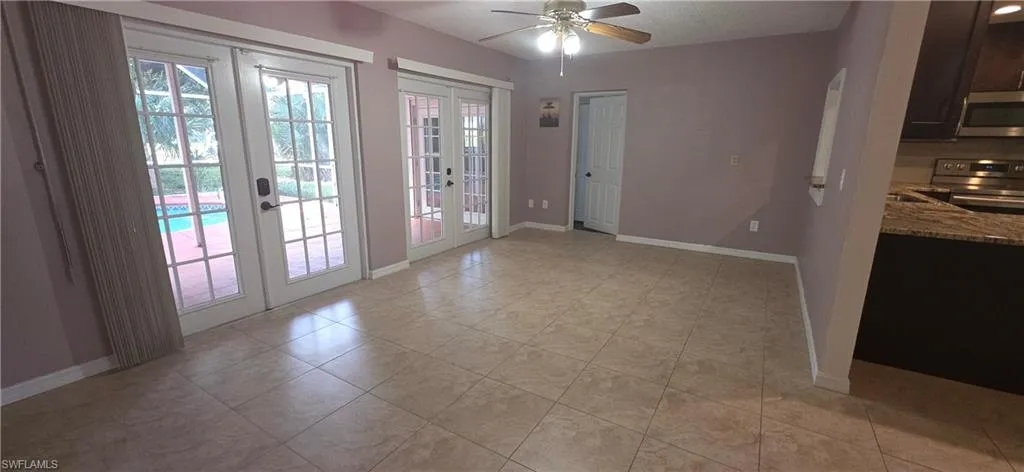 family room access to pool featuring french doors, ceiling fan, arched walkways, and tile patterned flooring