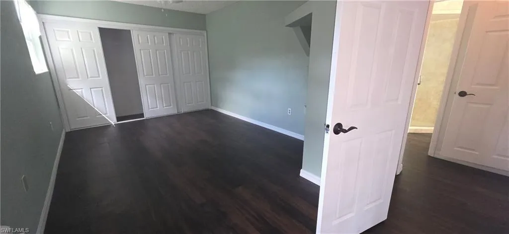 Unfurnished bedroom with a closet and dark wood finished floors