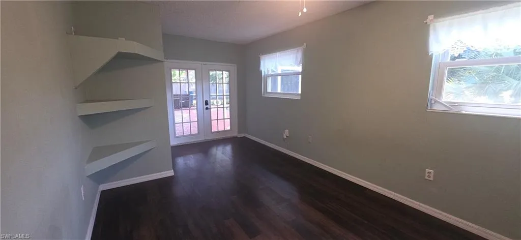 Unfurnished bedroom featuring french doors, dark wood-style floors, and a textured ceiling