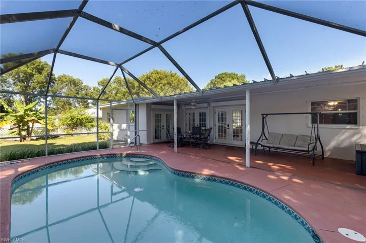 Swimming pool with french doors, a sunroom, and a lanai