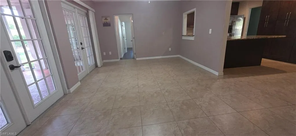 Family roomwith healthy amount of natural light, light tile patterned floors, and french doors