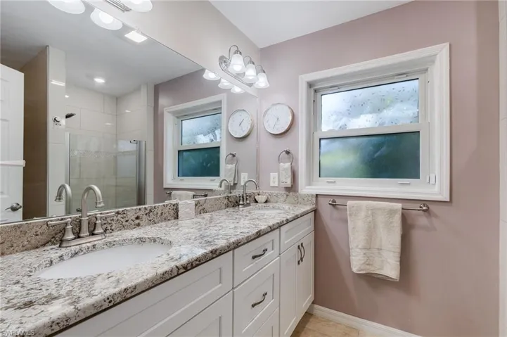 Primary bathroom featuring double vanity, a shower stall, and light tile patterned floors