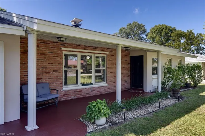 Property entrance with brick siding, covered porch, and a yard