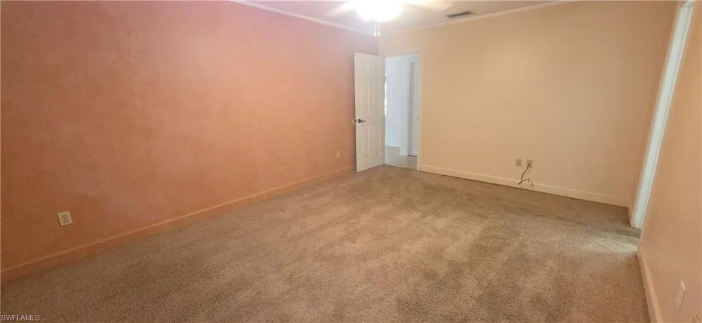 Primary bedroom featuring light colored carpet, ornamental molding, and a ceiling fan