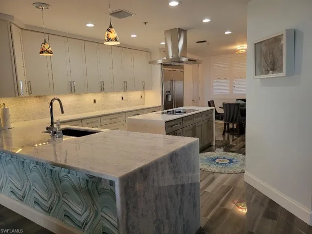 Kitchen featuring light stone counters, hanging light fixtures, dark wood finished floors, recessed lighting, and tasteful backsplash