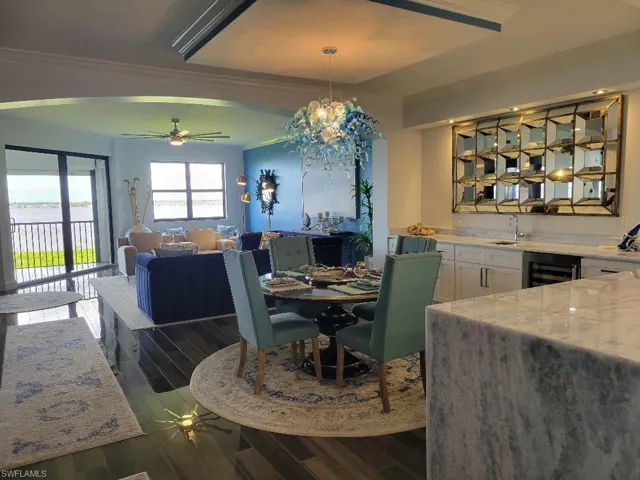 Dining area with crown molding, ceiling fan, dark wood-style floors, and beverage cooler