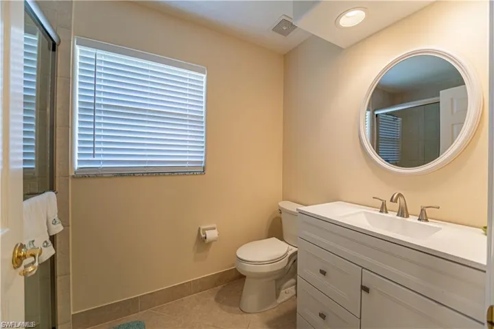 Bathroom featuring vanity, light tile patterned floors, a tile shower, and recessed lighting