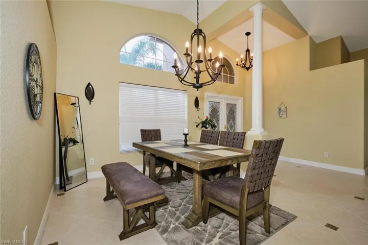 Dining room with light tile patterned floors, lofted ceiling, and suspended lighting