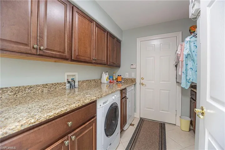 Laundry room with cabinet space, light tile patterned floors, and washer and dryer