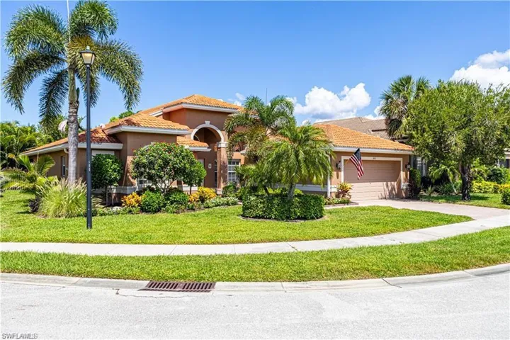 Mediterranean / spanish-style home with a tile roof, a front lawn, an attached garage, driveway, and stucco siding