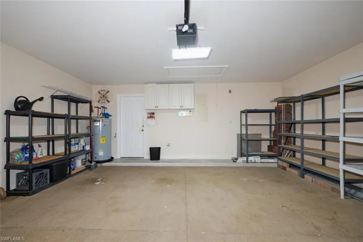Garage featuring a garage door opener, electric water heater, and electric panel