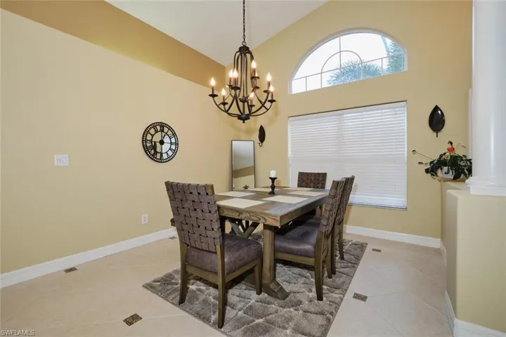 Dining room with light tile patterned flooring, lofted ceiling, and suspended lighting