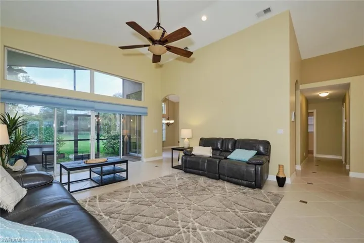 Living room featuring a high ceiling, arched walkways, a ceiling fan, light tile patterned floors, and recessed lighting