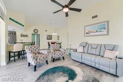 Living area with wood finished floors, vaulted ceiling, and a ceiling fan