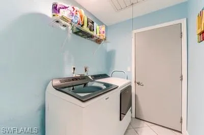 Laundry area featuring light tile patterned floors and independent washer and dryer
