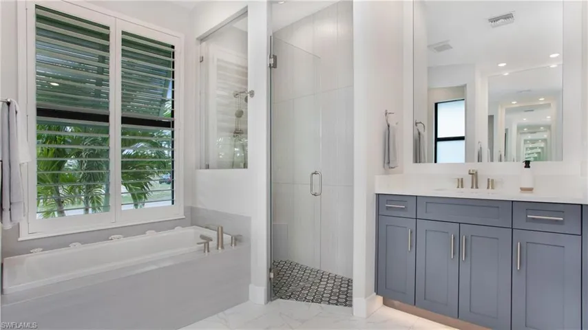Bathroom featuring vanity and separate shower and tub