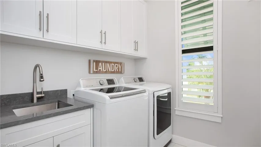 Clothes washing area with sink, cabinets, and washing machine and clothes dryer
