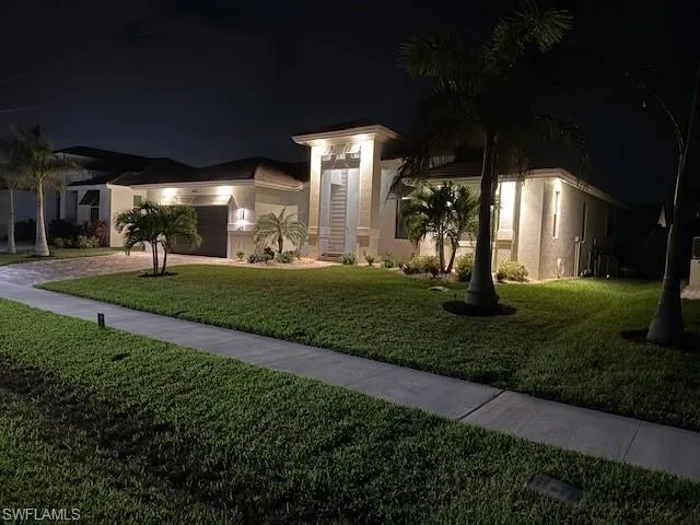 View of front of property with a garage and a yard