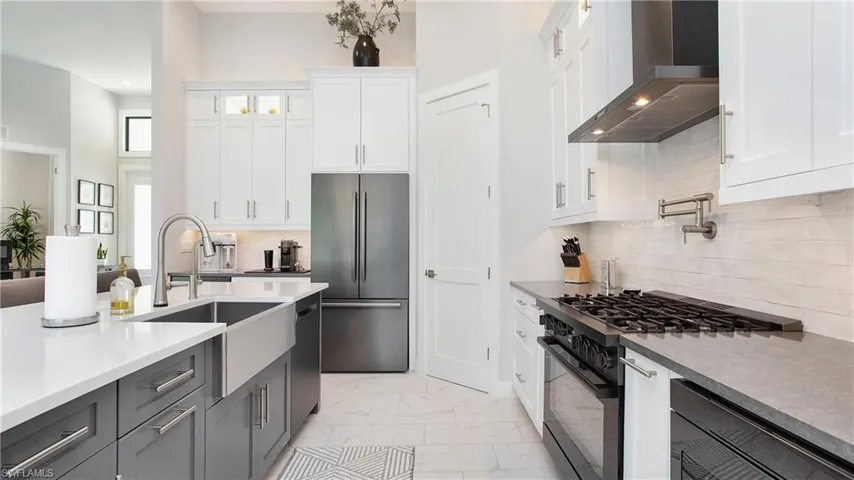 Kitchen featuring stainless steel appliances, white cabinetry, wall chimney range hood, gray cabinets, and sink