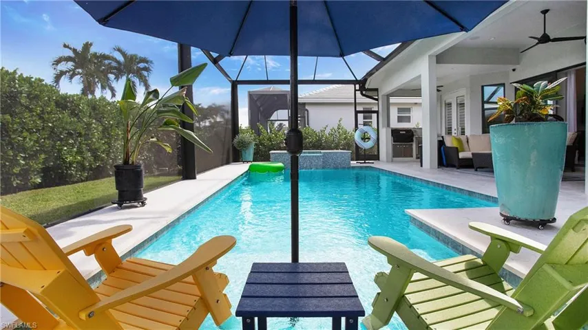 View of pool with glass enclosure, a patio area, and ceiling fan