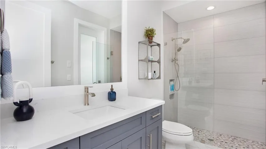 Bathroom featuring vanity, toilet, and tiled shower
