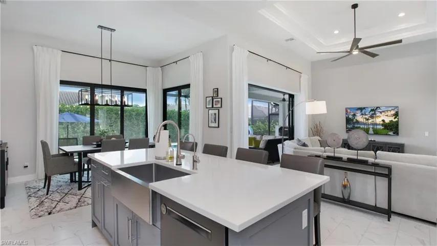 Kitchen with gray cabinets, hanging light fixtures, a center island with sink, and sink