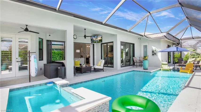 View of pool featuring glass enclosure, a patio area, french doors, and ceiling fan