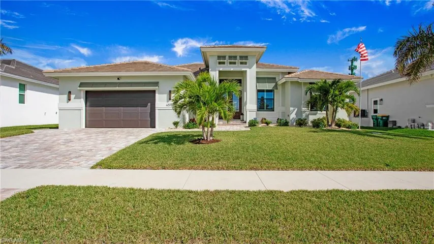 View of front of property with a garage and a front lawn